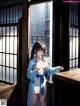 A woman in a blue robe standing in front of a window.