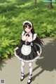 A woman in a maid outfit is walking down a path.