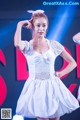 A woman in a white dress is dancing on stage.