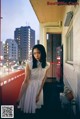 A woman in a white dress standing on a balcony.