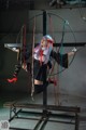 A woman in a black dress and red shoes is suspended on a swing.