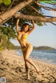 A woman in a yellow bikini standing on a beach.