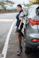 A woman standing next to a car on the side of the road.