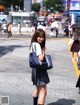 A woman in a school uniform is walking down the street.