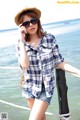 A woman in shorts and a hat talking on a cell phone.