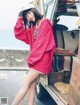 A woman in a red hoodie leaning against the back of a truck.