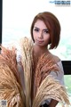 A woman holding a bunch of dried grass in front of a window.