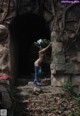 A naked woman standing in front of a stone archway.