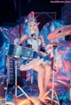 A woman in a blue and white dress playing a drum set.